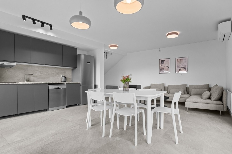 Világos nappali kanapéval és beépített konyhával, nyitott alaprajzon