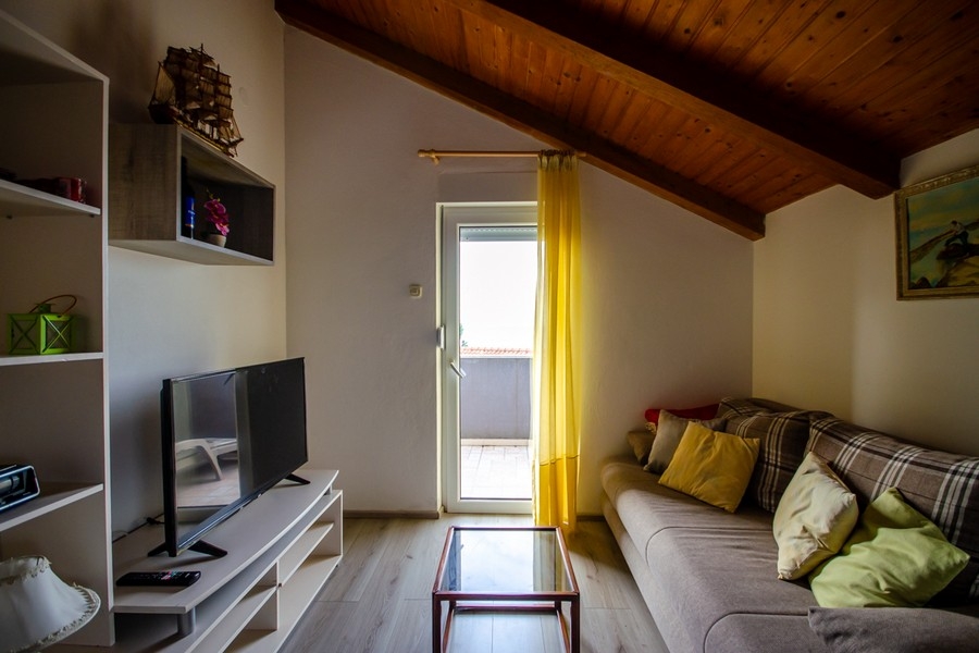 Nappali a tetőtérben kanapéval és kijárattal az erkélyre