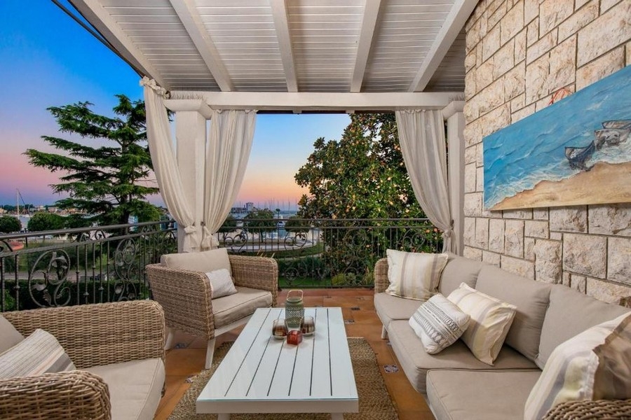 Erkély nappali bútorokkal és tengerre néző kilátással a naplementekor