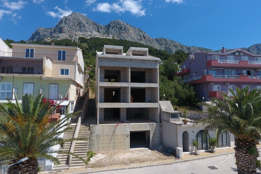 Kilátás a befejezetlen apartmanházra a Biokovo hegyekkel