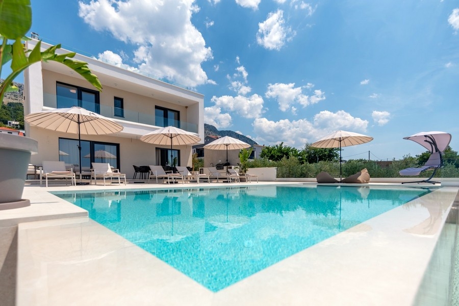 Medence napozóágyakkal a villa előtt