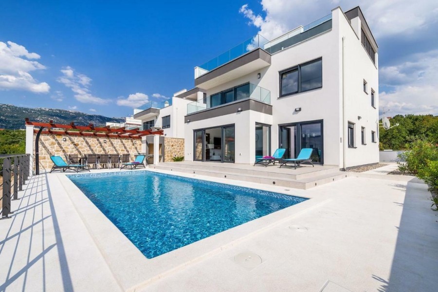 Fehér villa medencével és napozóágyakkal